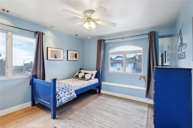 bedroom with ceiling fan, baseboards, and wood finished floors