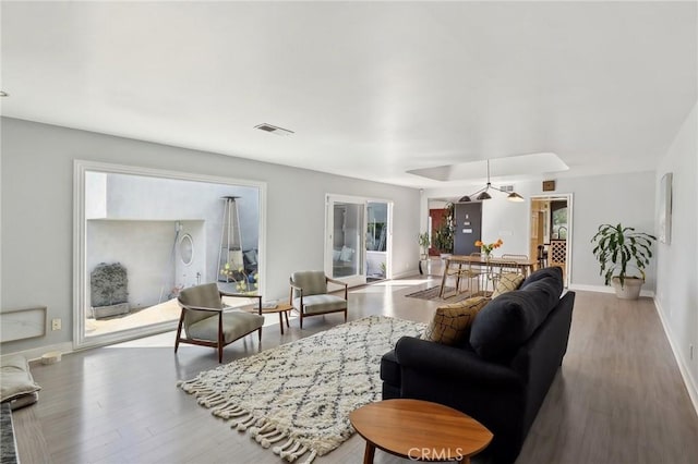 living area with visible vents, baseboards, and wood finished floors