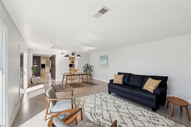 living room featuring light wood-type flooring, baseboards, and visible vents