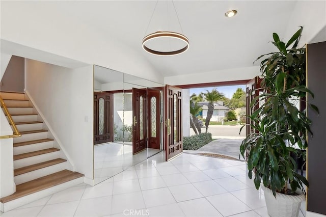 entrance foyer with vaulted ceiling, stairway, and light tile patterned flooring