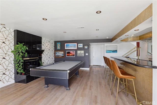 recreation room featuring recessed lighting, a large fireplace, wood finished floors, visible vents, and a dry bar