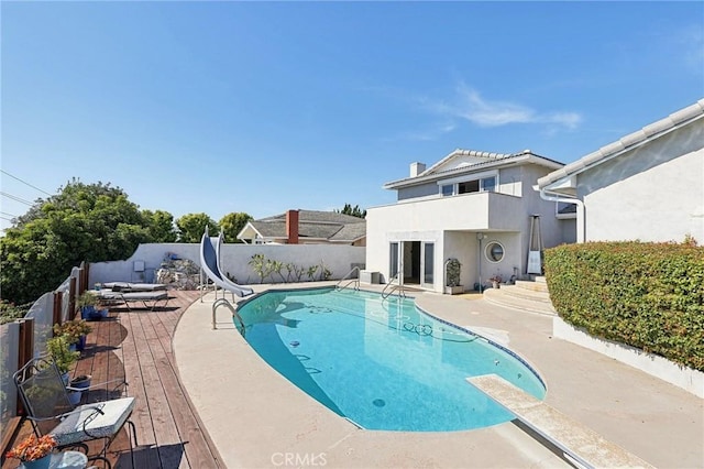 view of pool with a fenced backyard, a fenced in pool, a diving board, and a water slide