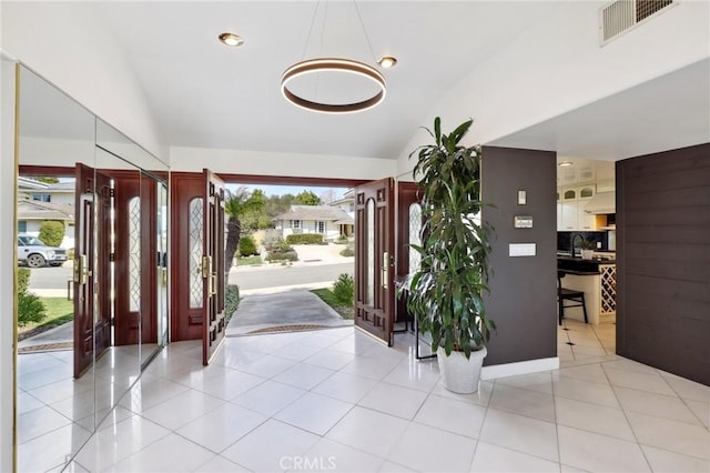 entryway featuring lofted ceiling, light tile patterned flooring, and visible vents