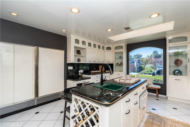 5726 Sunmist Dr, Rancho Palos Verdes, CA 90275 - kitchen featuring a kitchen island with sink, recessed lighting, decorative backsplash, dark stone counters, and white cabinets