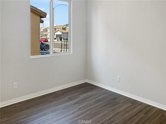 spare room featuring dark wood-style floors and baseboards