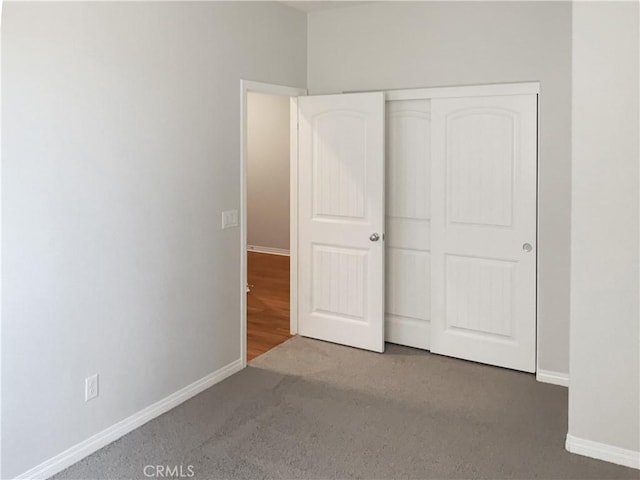 unfurnished bedroom featuring carpet floors, a closet, and baseboards