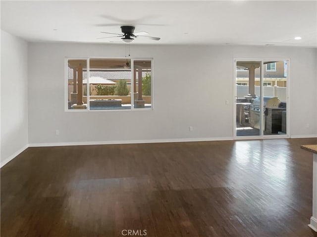 spare room featuring ceiling fan, baseboards, and dark wood-type flooring