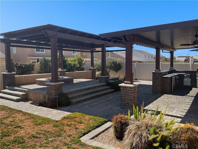 view of patio / terrace featuring exterior kitchen, fence, and a ceiling fan