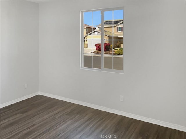 unfurnished room featuring dark wood-style flooring and baseboards