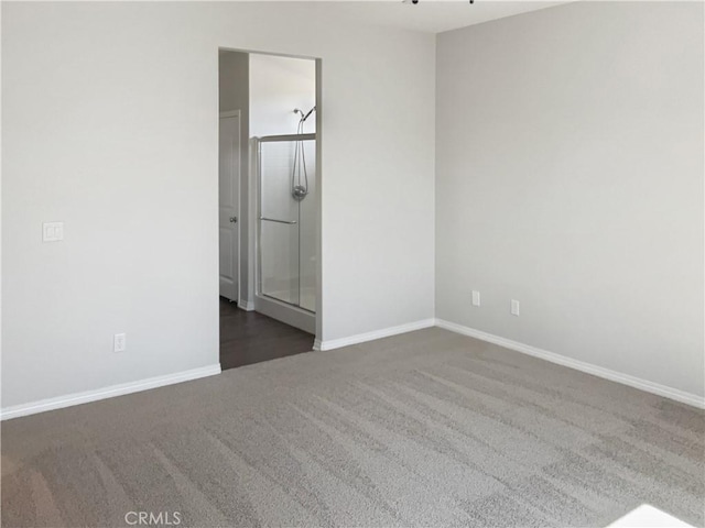 spare room featuring dark carpet and baseboards