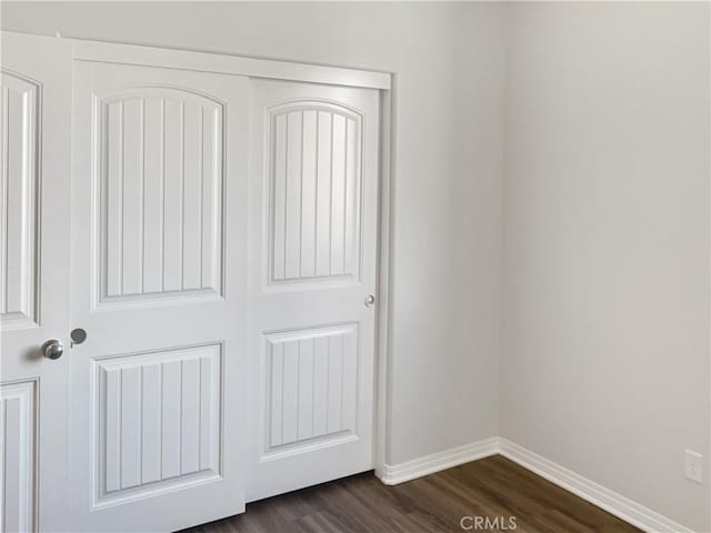 interior space with a closet, dark wood finished floors, and baseboards