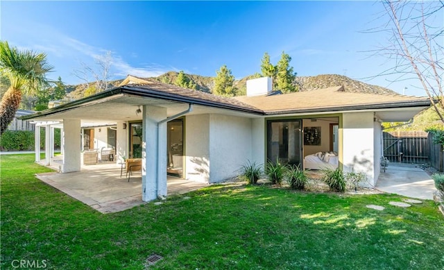 back of property with a lawn, a patio, fence, and stucco siding