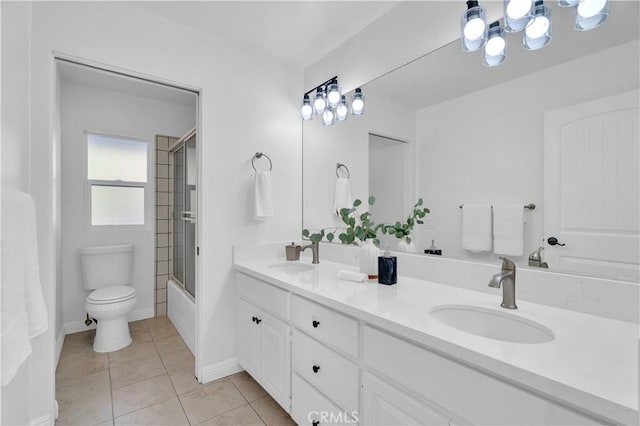 bathroom featuring tile patterned flooring, enclosed tub / shower combo, a sink, and toilet