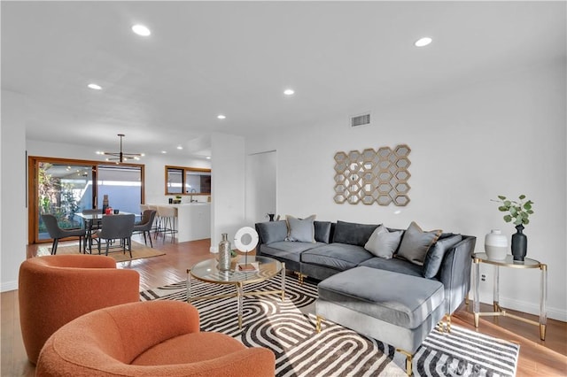 living room with baseboards, light wood finished floors, visible vents, and recessed lighting