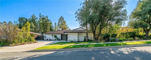 ranch-style house featuring driveway, a front lawn, and stucco siding