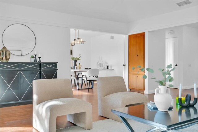 interior space with baseboards, wood finished floors, visible vents, and an inviting chandelier