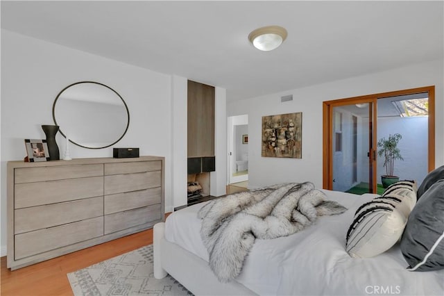 bedroom with light wood-type flooring, visible vents, and access to exterior