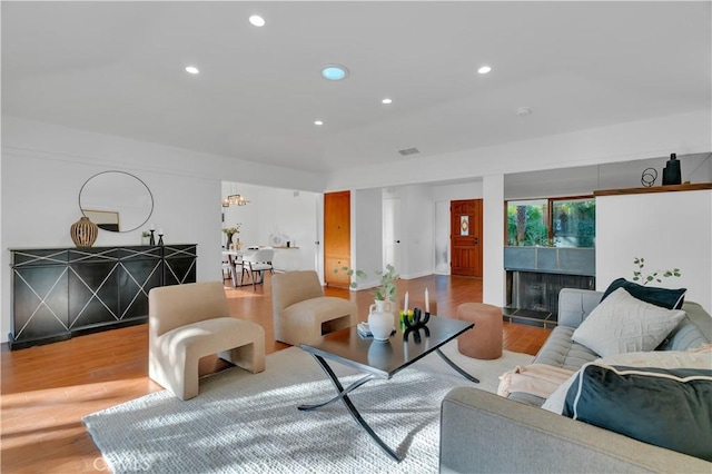 living area featuring recessed lighting, visible vents, a tiled fireplace, and light wood finished floors