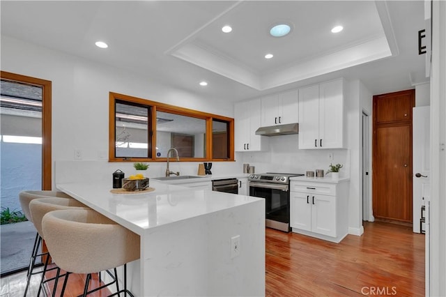 kitchen featuring under cabinet range hood, a sink, white cabinets, light countertops, and stainless steel electric stove