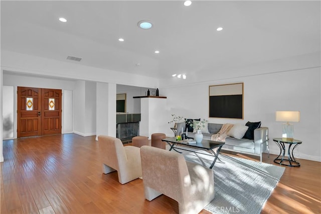 living area with recessed lighting, a fireplace, visible vents, and light wood-style floors