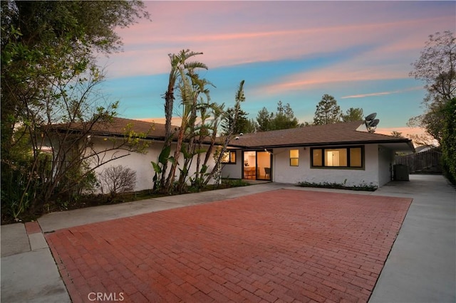 ranch-style home featuring fence, decorative driveway, and stucco siding