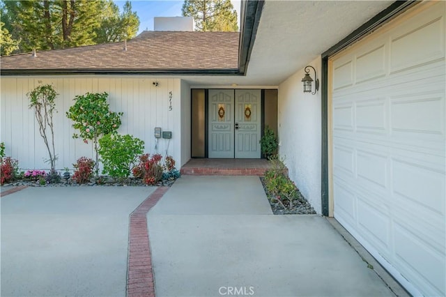 property entrance featuring a garage and roof with shingles