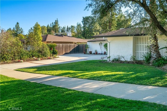 single story home with a front lawn, fence, and stucco siding