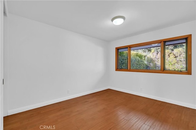 spare room featuring baseboards and wood finished floors