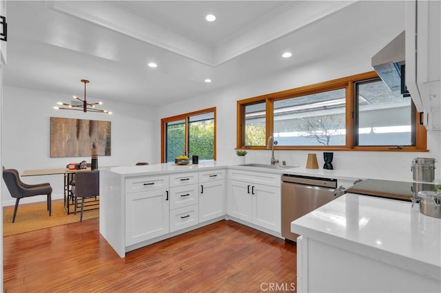 kitchen featuring pendant lighting, light countertops, white cabinets, a sink, and dishwasher