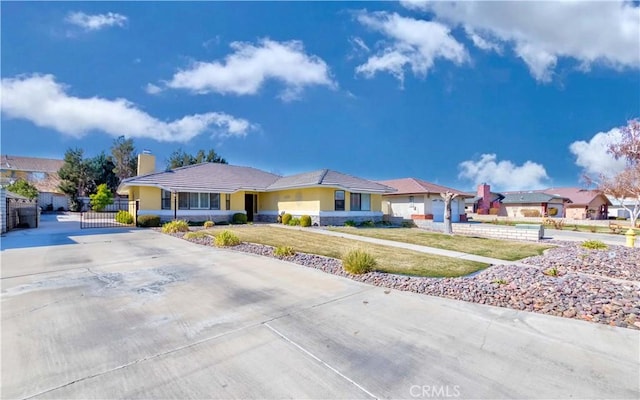 view of front of house with a chimney, stucco siding, concrete driveway, fence, and a residential view