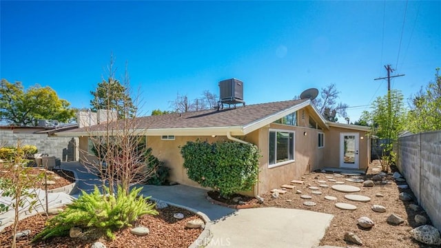 view of home's exterior featuring a shingled roof, fence, cooling unit, a patio area, and stucco siding