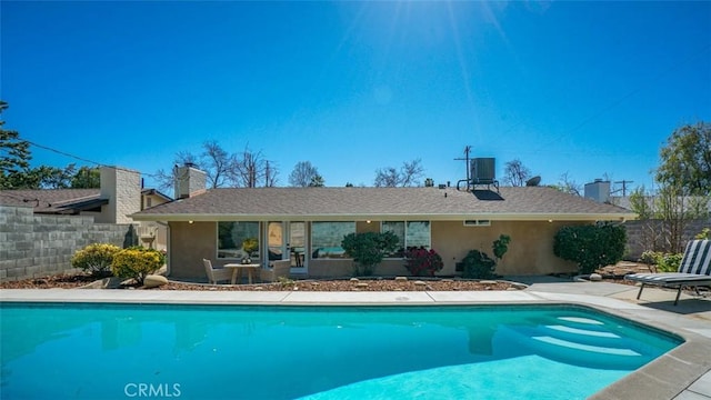 rear view of house featuring a fenced in pool, a patio, and stucco siding