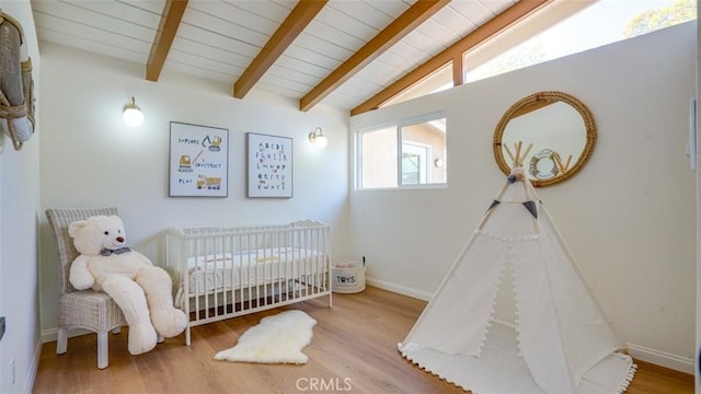 bedroom with a crib, baseboards, wood ceiling, wood finished floors, and vaulted ceiling with beams