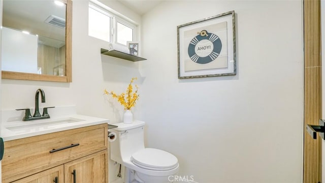 half bathroom featuring toilet, visible vents, and vanity