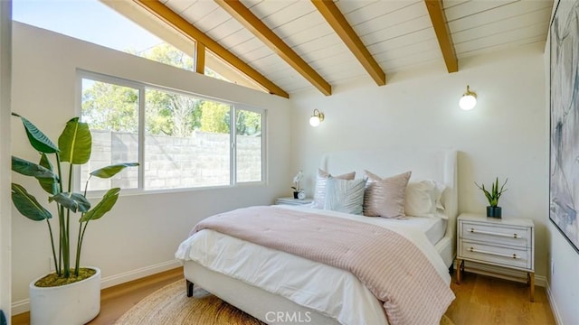 bedroom with vaulted ceiling with beams, baseboards, and wood finished floors