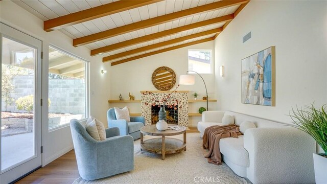 living area with a wealth of natural light, visible vents, a fireplace, and lofted ceiling with beams