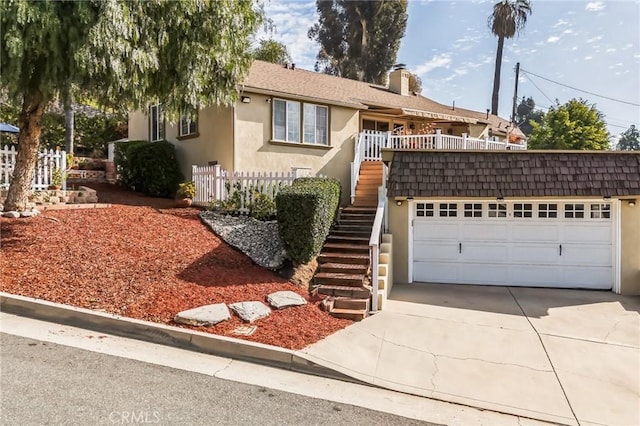 view of front of house featuring fence, driveway, stairway, and stucco siding