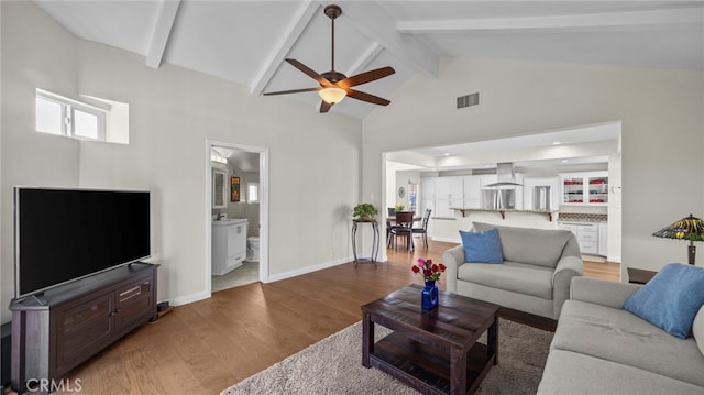 living area with beam ceiling, visible vents, baseboards, and wood finished floors