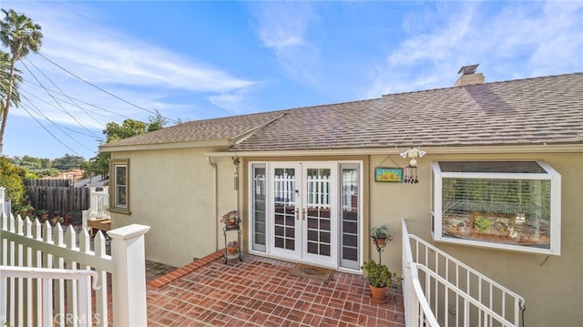 doorway to property featuring a patio, a chimney, roof with shingles, french doors, and stucco siding