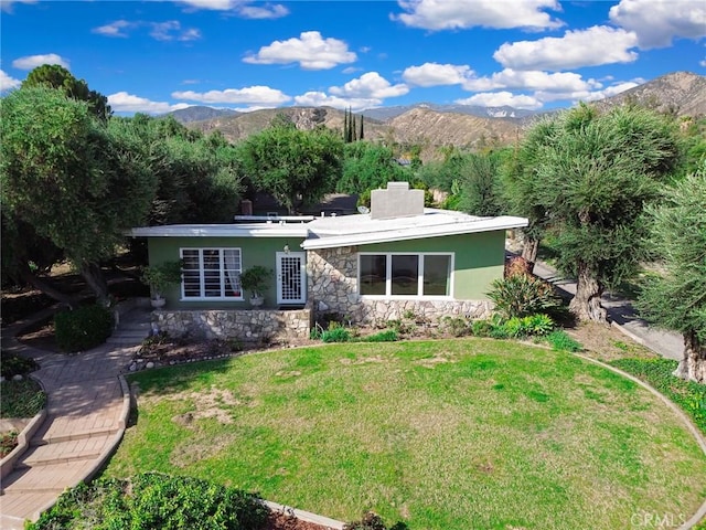 view of front of house featuring a front yard, a mountain view, and stucco siding