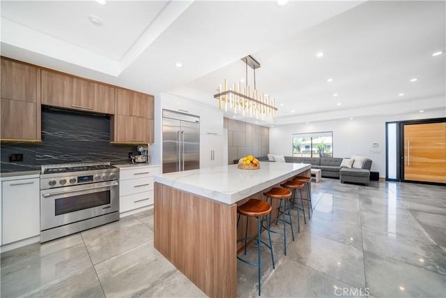 kitchen with high end appliances, white cabinets, modern cabinets, open floor plan, and a center island