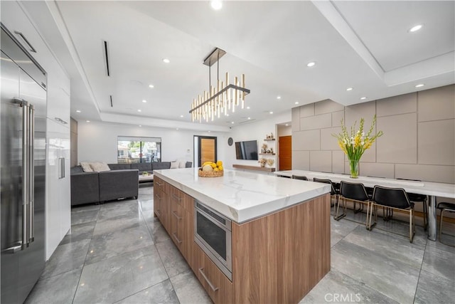 kitchen with built in appliances, open floor plan, a large island, brown cabinetry, and modern cabinets