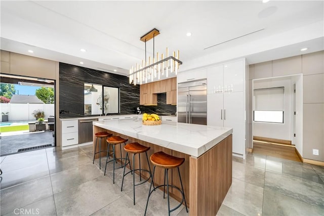 kitchen featuring a center island, hanging light fixtures, built in refrigerator, and modern cabinets