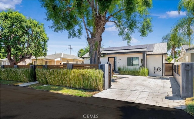 view of front of house featuring fence private yard, solar panels, and stucco siding