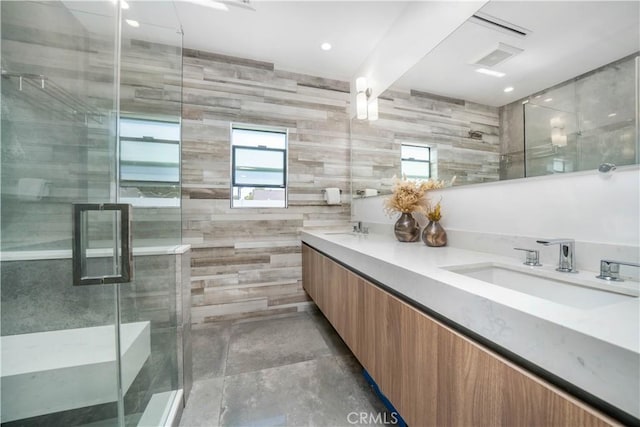 bathroom with double vanity, a stall shower, a sink, and tile walls