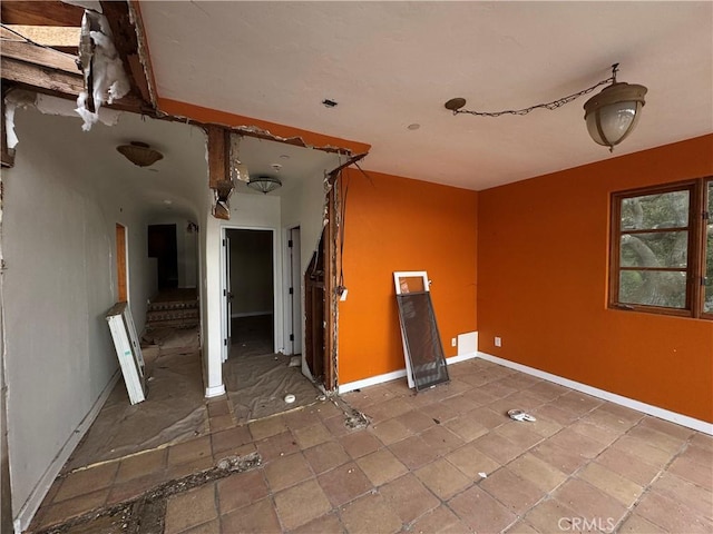 spare room featuring stairway and baseboards