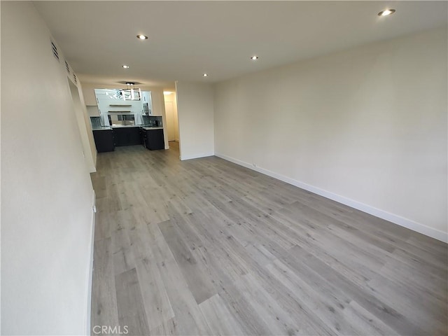 unfurnished living room featuring baseboards, light wood finished floors, visible vents, and recessed lighting