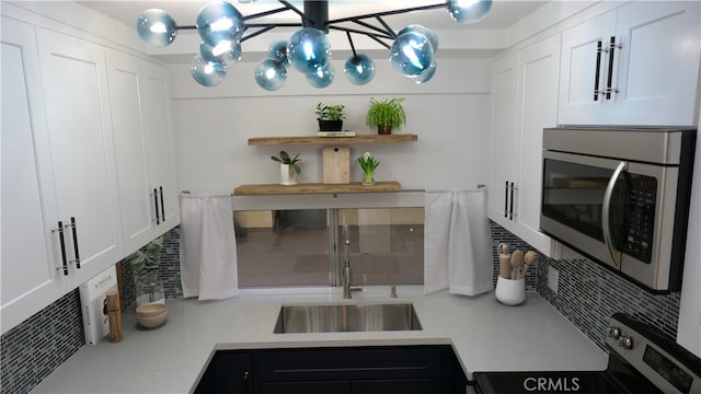 kitchen featuring white cabinets, appliances with stainless steel finishes, light countertops, open shelves, and a sink