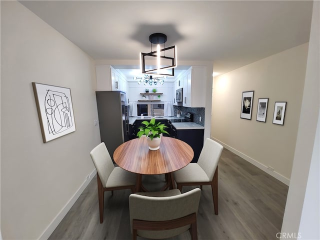 dining room featuring an inviting chandelier, baseboards, and wood finished floors