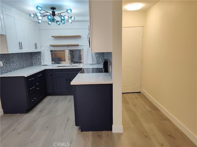 kitchen featuring dark cabinets, light countertops, white cabinets, and light wood-style floors